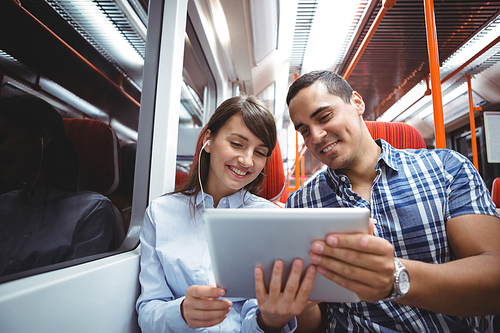 Smiling executives using digital tablet travelling in train