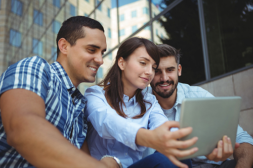 Smiling executives using digital tablet outside office building