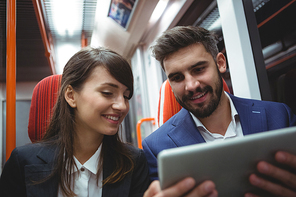 Smiling executives using digital tablet travelling in train