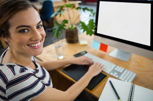 Portrait of smiling female graphic designer working on computer in creative office
