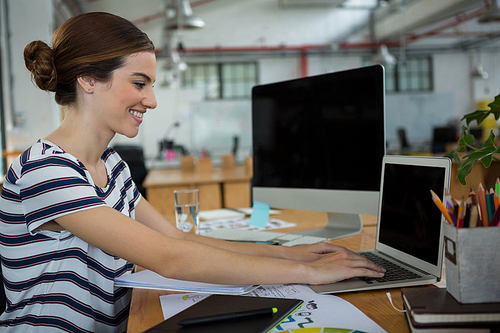 Female graphic designer using laptop in creative office