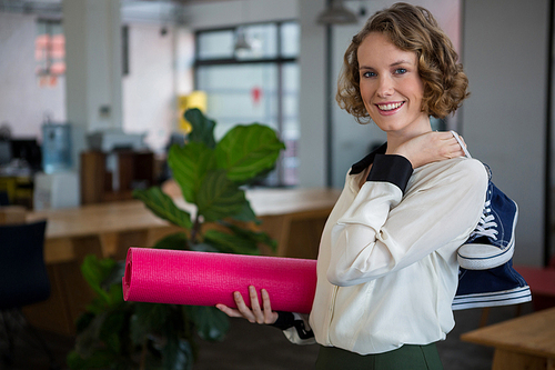 Portrait of female graphic designer with sneakers and yoga mat