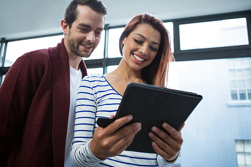 Man and woman discussing over digital tablet in office