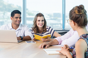 Smiling business colleagues interacting with each other in meeting at office