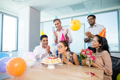 Smiling colleagues celebrating birthday of woman in office