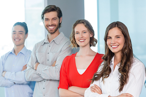 Portrait of business executives with arms crossed smiling while standing in office