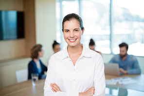 Portrait of beautiful business executive standing with her arms crossed in office