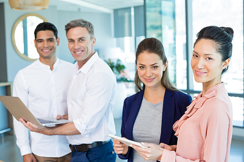 Portrait of confident architects holding laptop and digital tablet in office