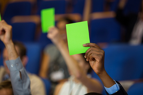 Business executives show their approval by raising hands at conference center