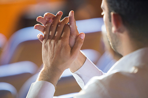 Business executive clapping while listening to speech at conference center