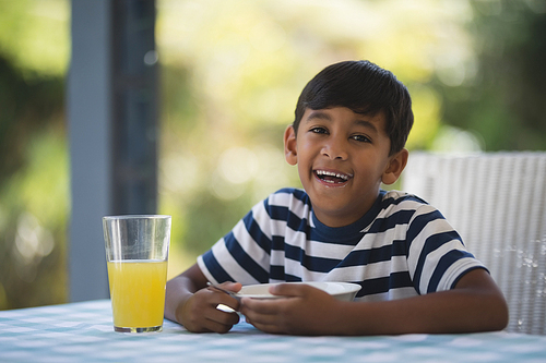 Portrait of happy boy having breakfast while sitting at table