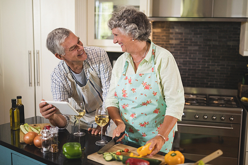 Smiling senior couple looking at each other while standing in kitchen at home