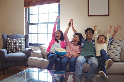 Smiling family watching television together in living room at home