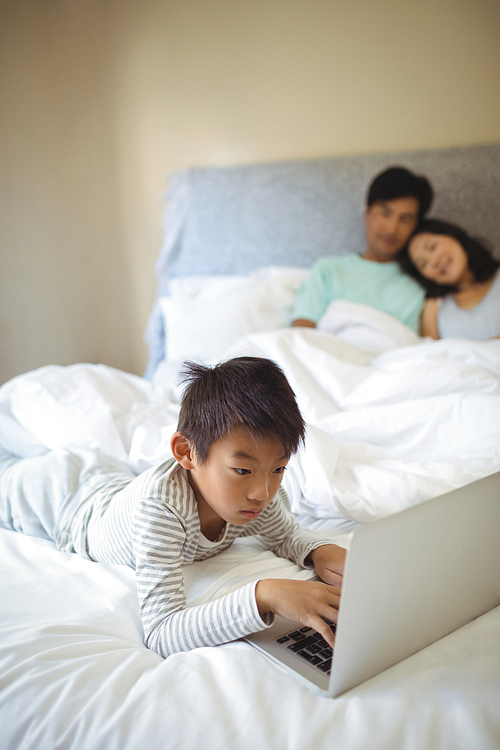 Boy using laptop in bedroom at home
