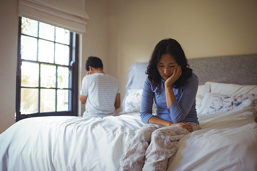 Couple ignoring each other in bedroom at home