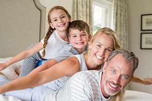 Portrait of happy family stacking on top of each other on the bed in bedroom