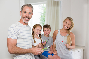 Portrait of smiling parents and kids brushing teeth in bathroom at home