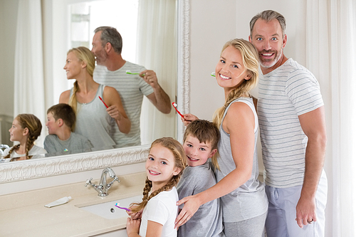 Portrait of smiling parents and kids brushing teeth in bathroom at home
