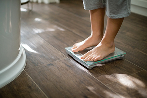 Boy checking his weight on weight scale at home