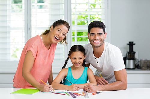 Portrait of smiling parents and daughter drawing in kitchen at home