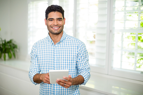 Portrait of smiling man using digital tablet in living room at home