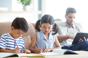 Attentive siblings doing homework in living room at home