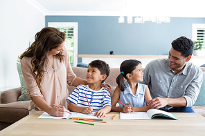 Parents assisting their kids in doing homework at home