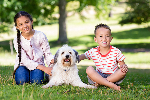 Portrait of siblings sitting with their pet dog in park