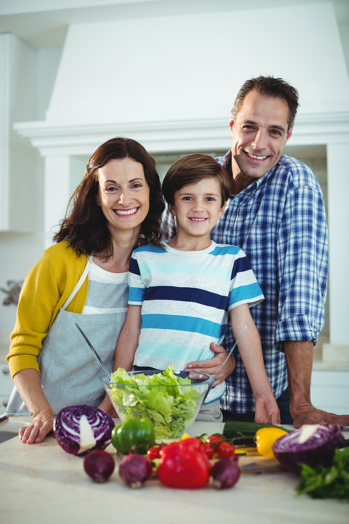 Portrait of parents and son preparing salad in kitchen at home
