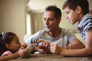 ather and kids using digital tablet in living room at home