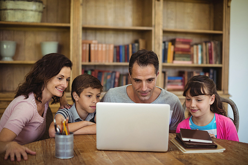 Parents and kids using laptop on table in study room at home