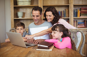 Parents and kids using laptop on table in study room at home