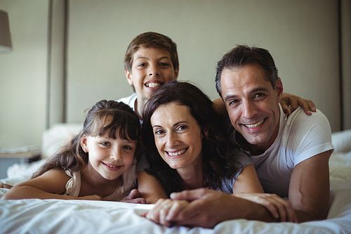 Portrait of happy family lying on bed in bedroom at home