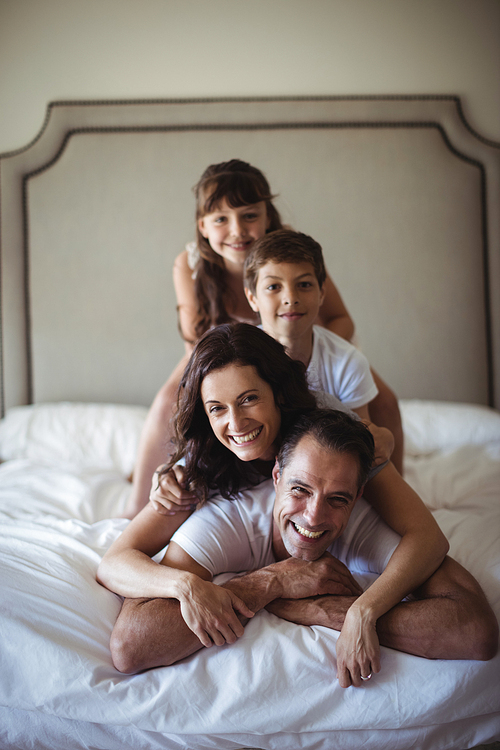 Portrait of happy family stacking on top of each other on the bed in bedroom