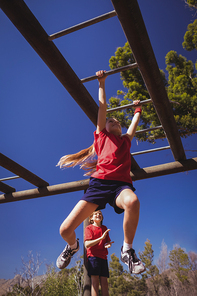 Girl climbing monkey bars during obstacle course training at boot camp