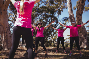 Female trainer instructing women while exercising in the boot camp on a sunny day