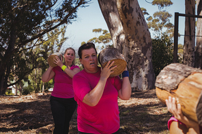 Group of women carrying a heavy wooden log during obstacle course in the boot camp