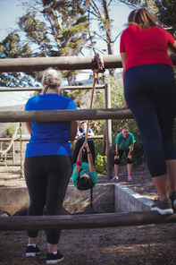 Fit woman climbing a rope during obstacle course training in the boot camp