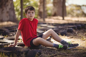 Portrait of boy relaxing on tyre during obstacle course during obstacle course in boot camp