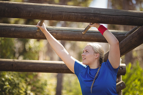 Determined woman exercising on monkey bar during obstacle course in boot camp