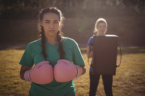 Determined woman wearing boxing gloves during obstacle course in boot camp