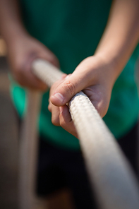 Mid-section of boy practicing tug of war during obstacle course training in the boot camp