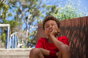 Upset boy sitting on staircase in the boot camp on a sunny day