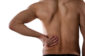 Midsection of shirtless sports player suffering from pain while standing against white background