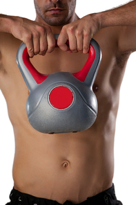 Midsection of shirtless sports player exercising with kettle bell while standing against white background