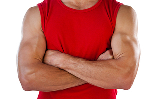 Midsection of sports player with arms crossed standing against white background