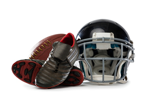 Close up of sports shoes with helmet and American football against white background