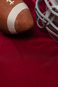 High angle view of helmet and American football on red jersey