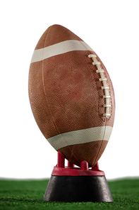 Close up of American football on tee at field against white background