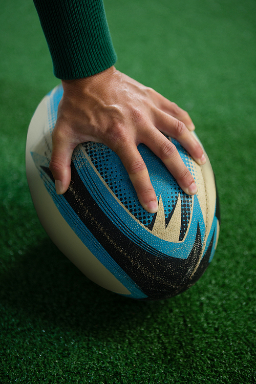 유토이미지 | Cropped image of hand holding rugby ball on playing field
